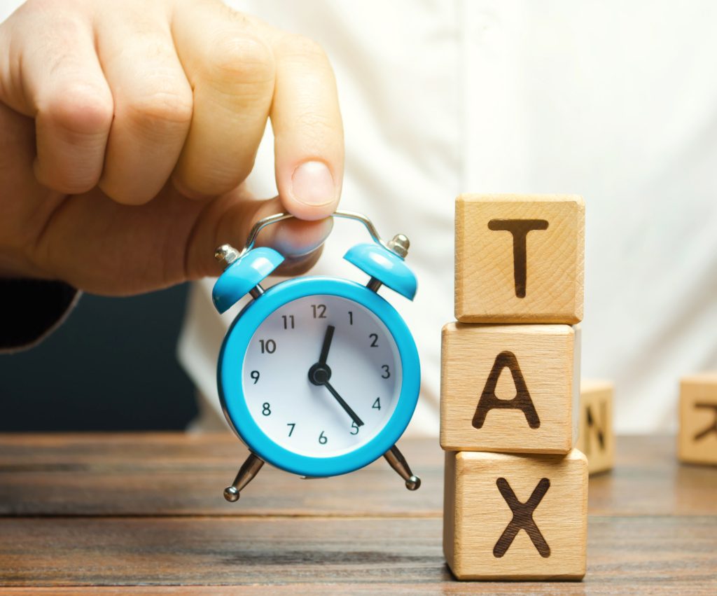 Understanding Tax System for Small Businesses businessmans hand holding a clock near the wooden gxlbaj5 (1)